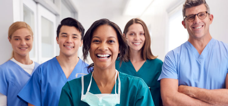 Five multi-cultural medical team members stand together in a hospital corridor.