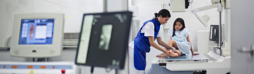 girl having her leg scanned by an x-ray machine.