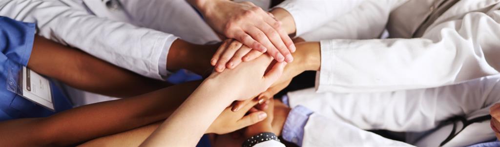 High angle shot of a group of medical practitioners joining their hands together in a huddle